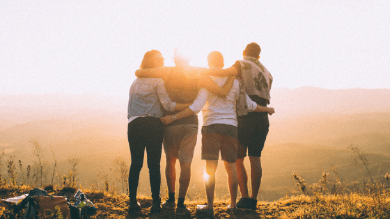 Four people looking at the sunset with their backs looking at the camera 