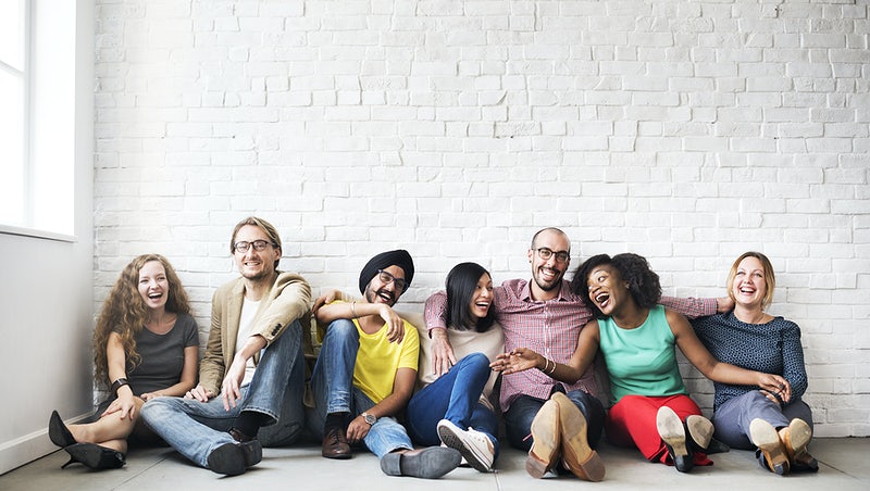 People from all backgrounds and experiences sitting and laughing in the floor, having a great time