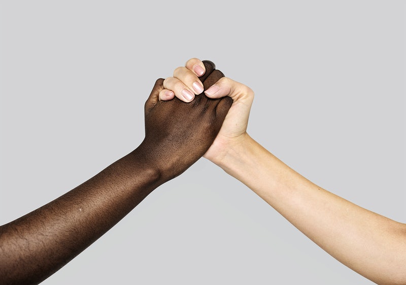 A white an a black hand holding each other to symbolize diversity and inclusion