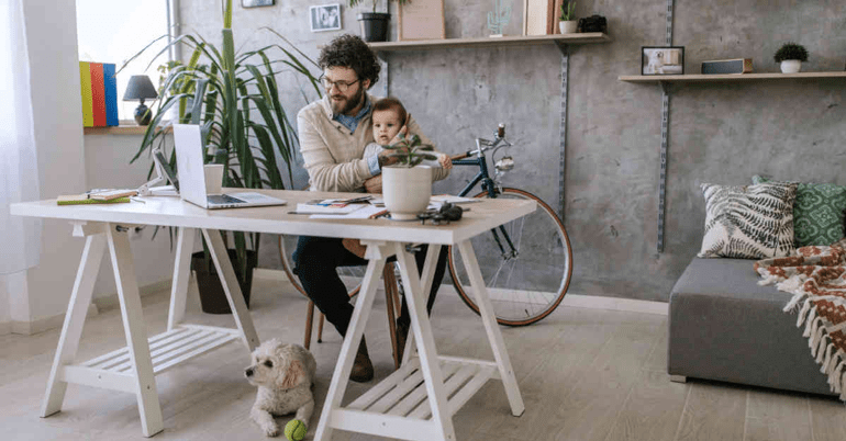 A father working from home with his dog and his baby son to represent the importance of a healthy work-life balance