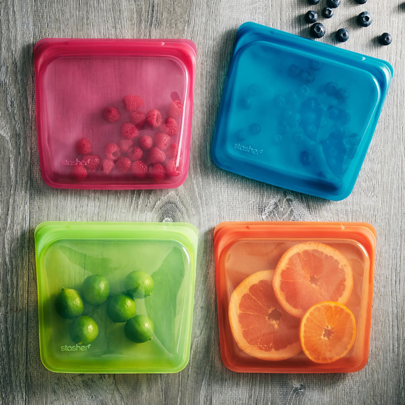 Red, blue, green, and orange stasher bags with fruits and berries inside
