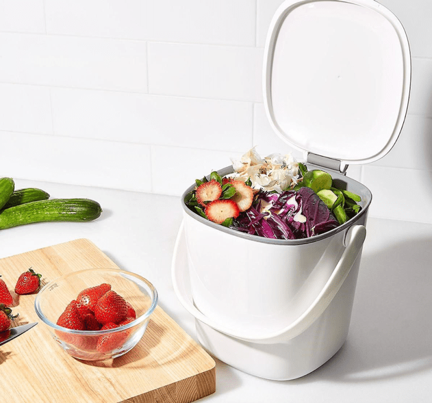 An OXO Compost Bin with fruits and veggies ready to be composted in the kitchen table